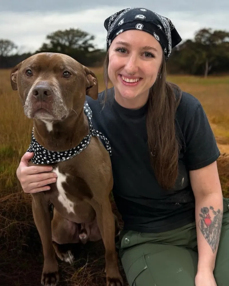 Kalie outdoors with her brown dog in a polka-dot bandana.